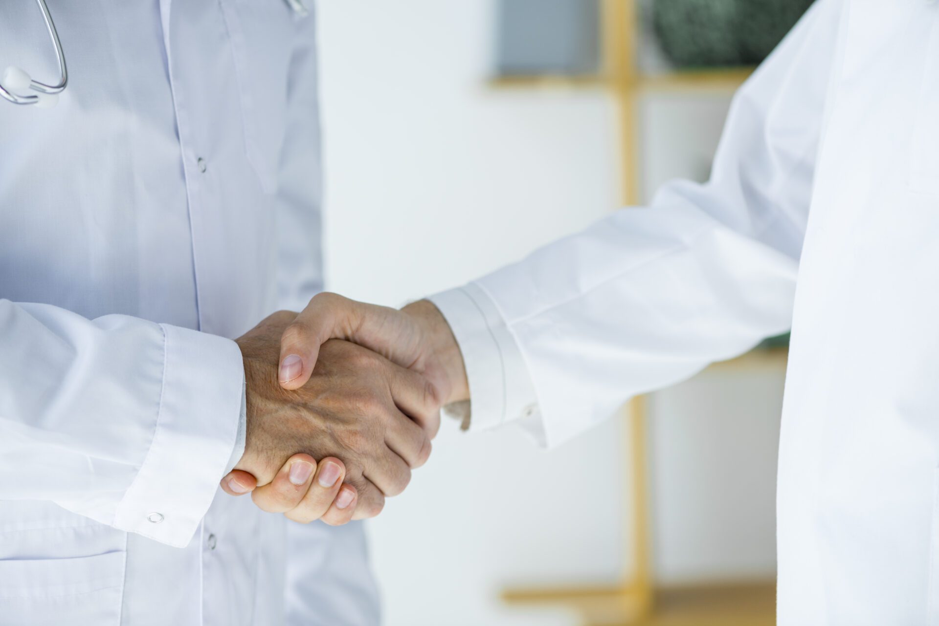Two doctors in white coats shaking hands in a hospital setting, symbolizing collaboration and professionalism in healthcare